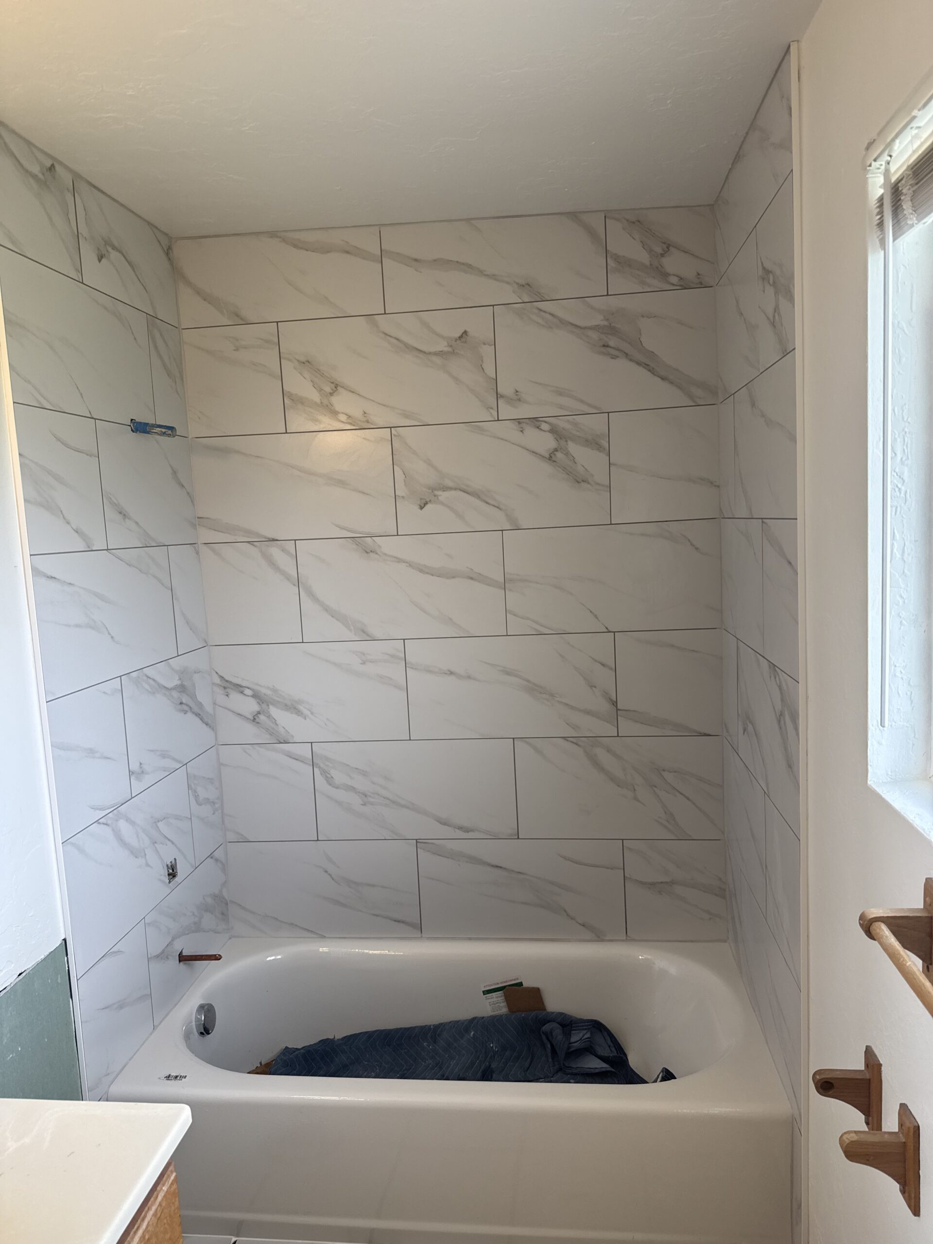 Marble-look porcelain tile tub surround installation in Utah bathroom by Bear Tile Flooring